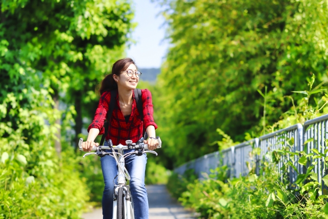 緑の中を自転車に乗る女性